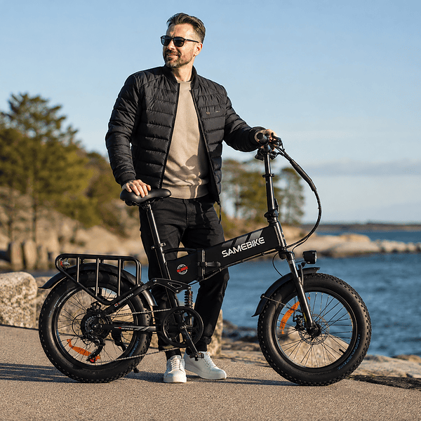 Mies seisoo taitettavan sähköpyörän kanssa meren rannalla.